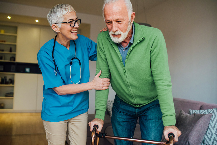 Caregiver assisting an older adult with mobility support at home during post-hospital recovery