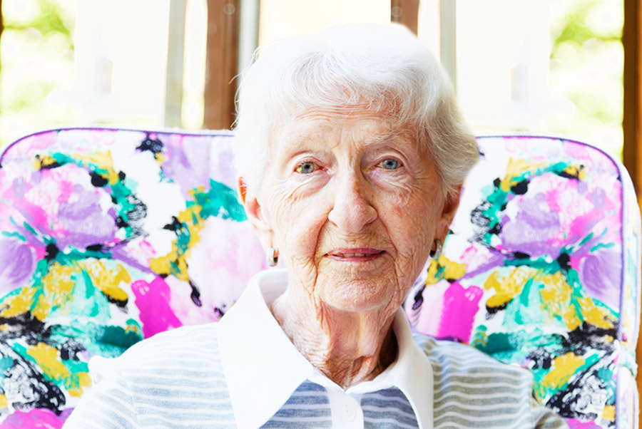 older woman sitting in a chair near a window in a bright home